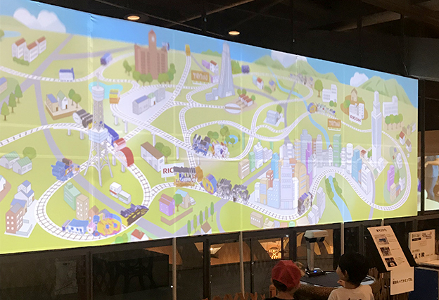画像：子どもたちの用紙に描いたイラストが、スクリーンの中を動き回る「作ろう！レールでつながるみんなの街」