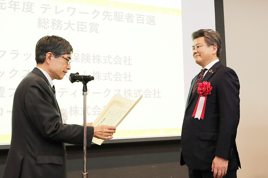 画像：寺田 稔 総務副大臣（左）より表彰状が授与される、リコージャパン 社長執行役員 坂主 智弘