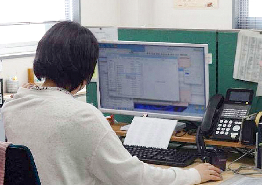 パソコン画面でファクス文書を確認する従業員の画像