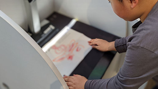 子どもが絵をスキャンしている画像