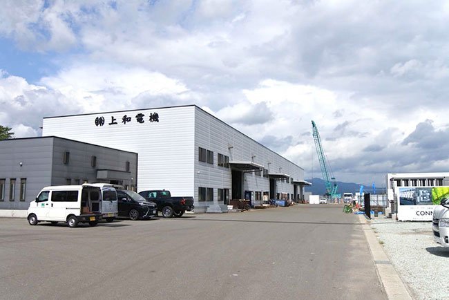 白い板金棟の先に見える青いクレーンの位置が塗装棟の建設現場