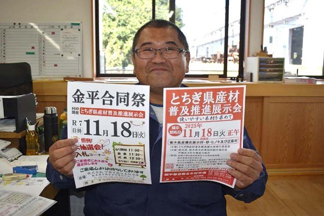 金平合同市のちらしを掲げ、満面の笑みを浮かべる社員。祭りの準備に余念がない