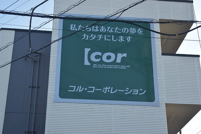 「私たちはあなたの夢をカタチにします」。社屋近くの自社ビルの看板には、古越社長の思いが掲げられている
