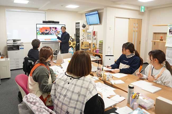 連島こども園の職員室で電子黒板を活用して会議を行う様子