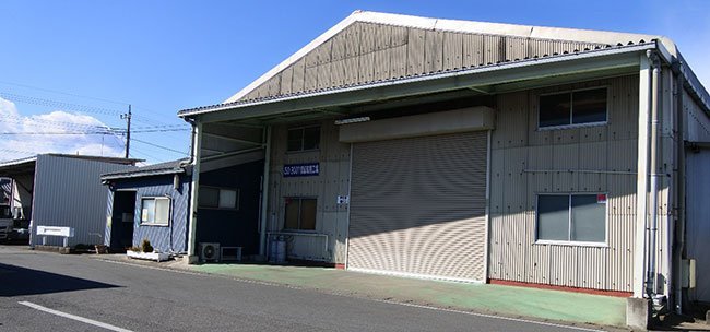 本社入口（左の青い建物）と第一工場の外観