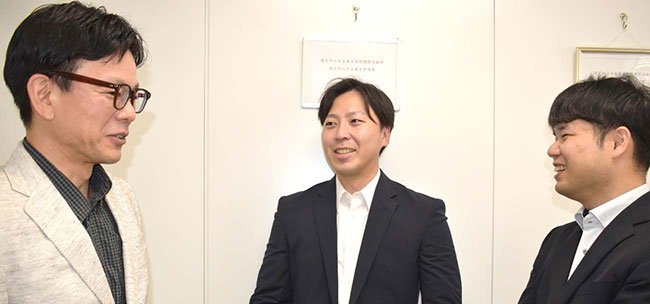 本社オフィスで、社員と雑談するDCアライブの水主誠社長＝中央