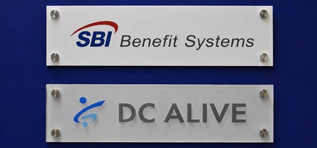 大阪市内の本社オフィスビルに掲げられたDCアライブのロゴ（下）。SBIベネフィット・システムズとの連携を象徴している。
