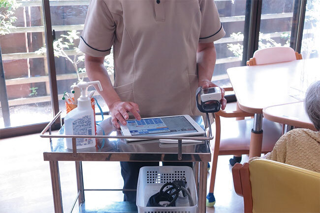 バイタル測定を利用者のそばで行い、タブレットに直接入力。パソコンに転記する作業が不要となった