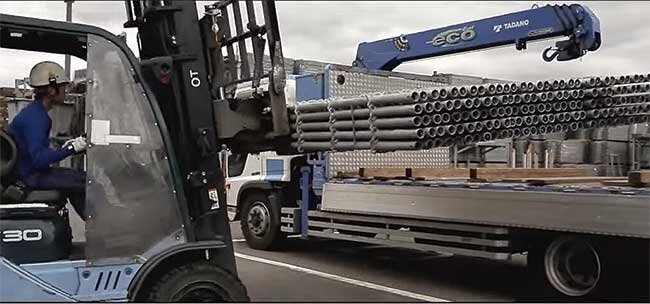 仮設機材置き場でのフォークリフトを使った機材の積み込み（会社案内ビデオより）