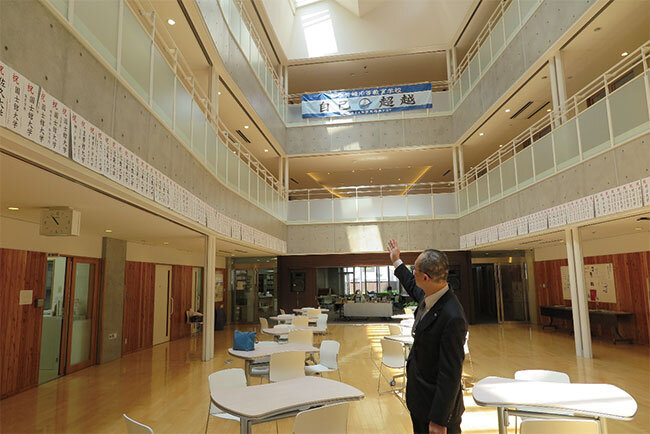 校内を案内する塩畑教頭、壁には卒業生が合格した大学名が貼り出されている