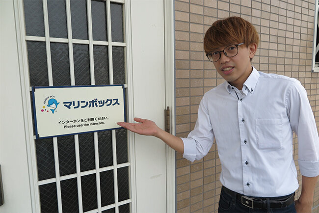 同社入り口前で長谷川一希氏