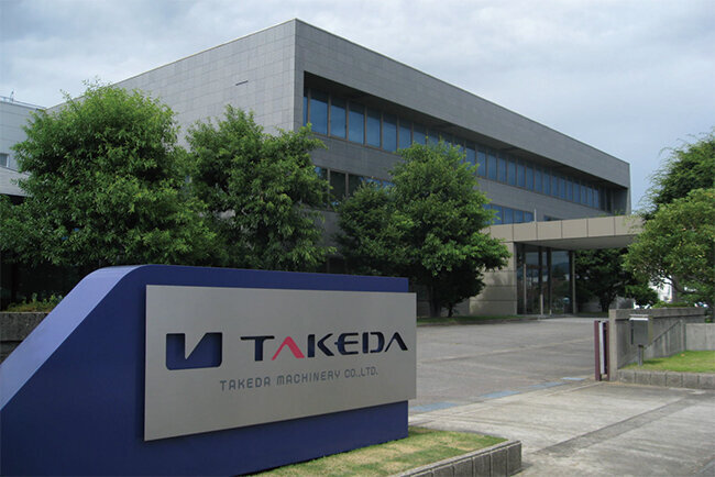 タケダ機械のコーポレートロゴと本社の外観