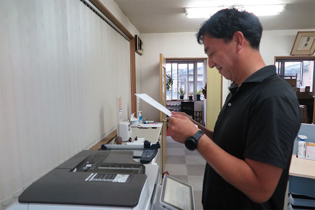 複合機の前で書類を確認する