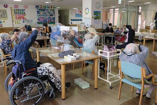 職員と一緒に身体をほぐすデイサービスの利用者たち