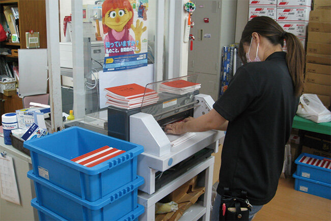 スタッフが冊子の断裁に取り組む様子