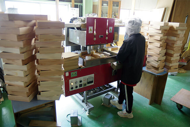 ベトナムから来た実習生によって、おせち料理を入れる木箱が次々に作られていく