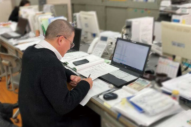 事務所でパソコンを見ている三谷社長