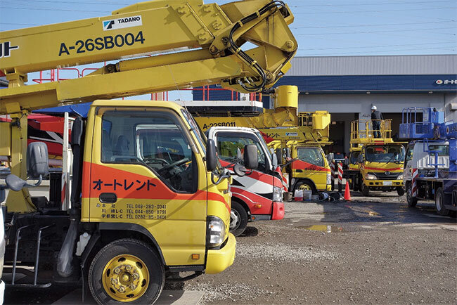 車両置き場「メインステーション鳩ヶ谷Pier」に並ぶ高所作業車。赤と黄色のボディカラーはウルトラマンガイアのデザインを参考にした