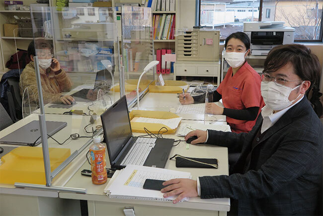 事務所のデスクで職員らと