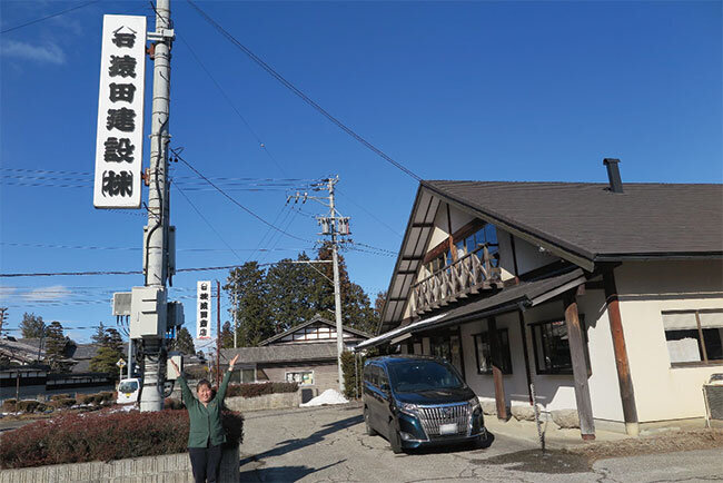 澄み渡った青空を背に社屋前で