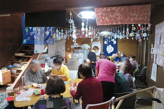 作品が飾られた室内で職員とレクリエーションを楽しむデイサービスの利用者