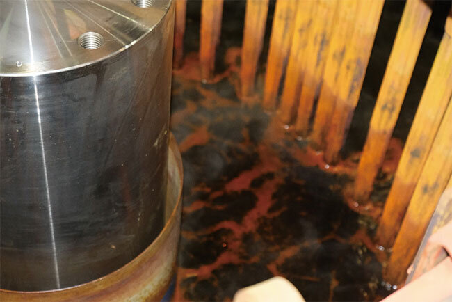 めっき槽に浸かった部品（左）。部品を取り囲んでいる茶色の棒は、通電させるためのトクシュ技研製高性能陽極