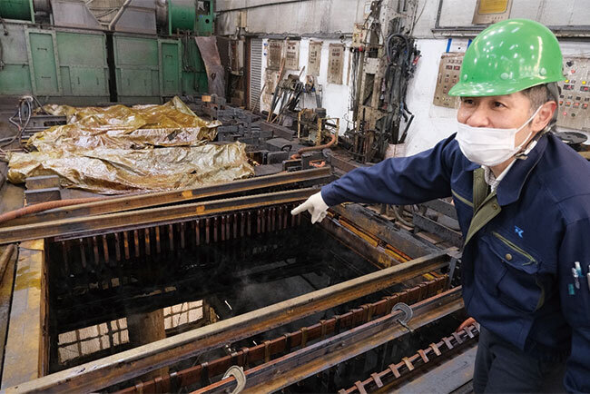 クロムめっき槽を示す古市社長。ミストが工場内にこもらないよう換気されている