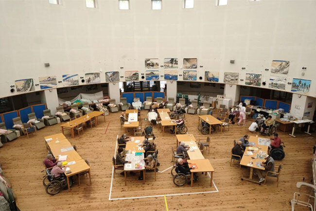 ドーム屋根の自然光が降り注ぐ円形ロビー。気持ちいい空間で過ごす入居者ら