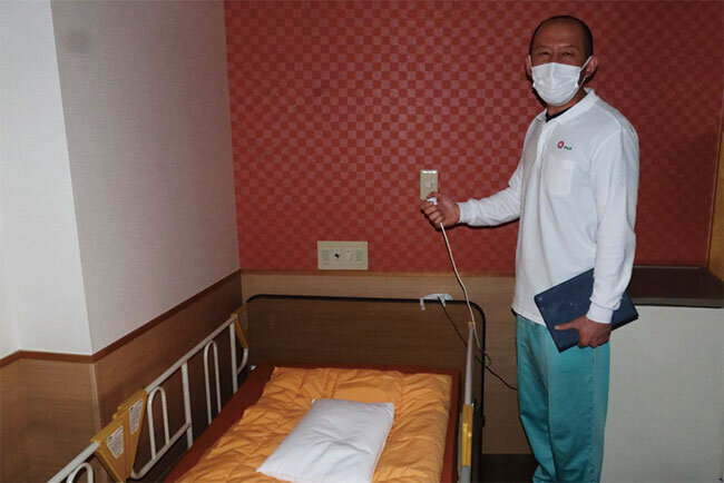 かつてのナースコール用ボタンを手にする職員。新しいシステムで「負担が激減した」という