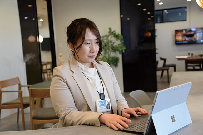 スタイリッシュにリノベーションされた本社の打ち合わせスペースで業務を行う経営企画部の荒井愛課長。支給されたSIMフリーのパソコンでどこでも業務ができる