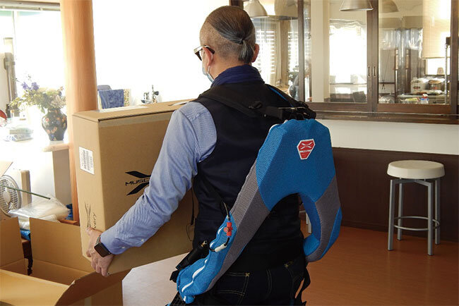 「アシストスーツを装着して荷物を持つ平川代表取締役