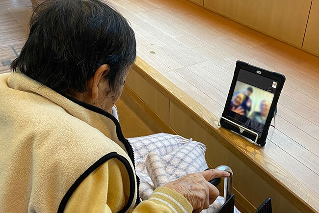 オンラインでの会話を楽しむお年寄り（実際には家族の方が鮮明に映っています）