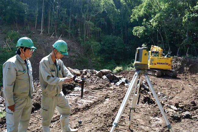 自動追尾計測機器をチェックする田村主任（左）とファム氏