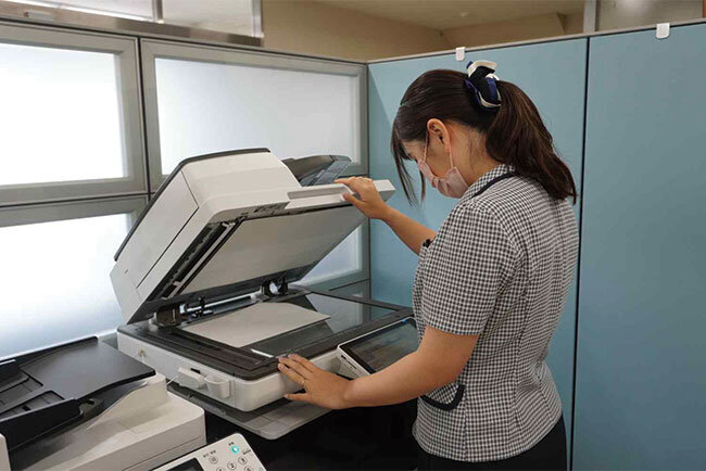 紙文書を複合機でスキャンする様子