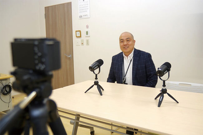 動画配信スタジオのカメラに向かいマイクの前に座る清水商事の清水正樹代表取締役
