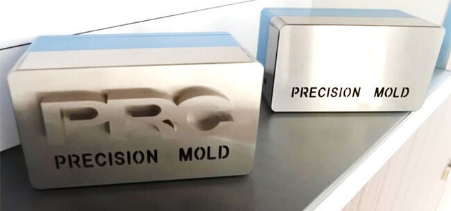 金型の材料で作ったデモ用製品。1枚の厚板にしか見えない鋼材（右）から社名が浮き出る（左）