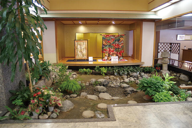 十日町友禅の着物が飾られ、せせらぎが流れるホテル双葉のロビー