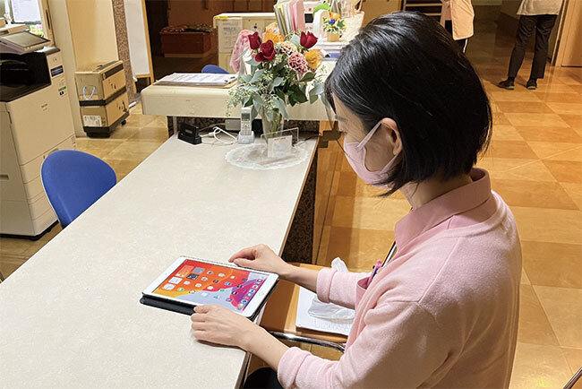 介護日誌をタブレットで書き込む介護職員。記入作業が省力化されたことで入居者と接する時間が増えたという