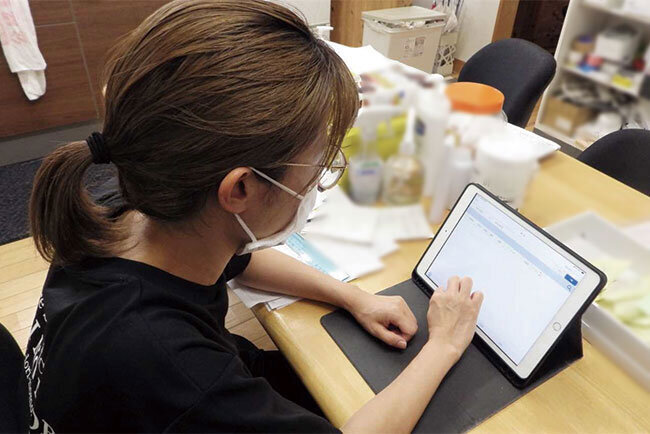 介護記録が入力されたタブレット画面をチェックする介護士のリーダー