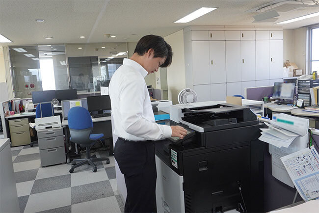 紙文書を複合機でスキャンしてデジタル化する様子