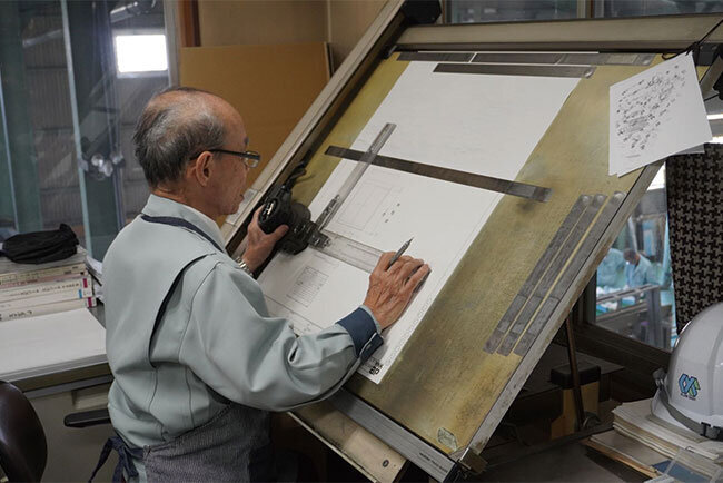 トレーシングペーパーに手描きで設計に取り組む社員もいる