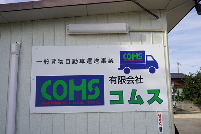 営業所に掲げているコムスの看板