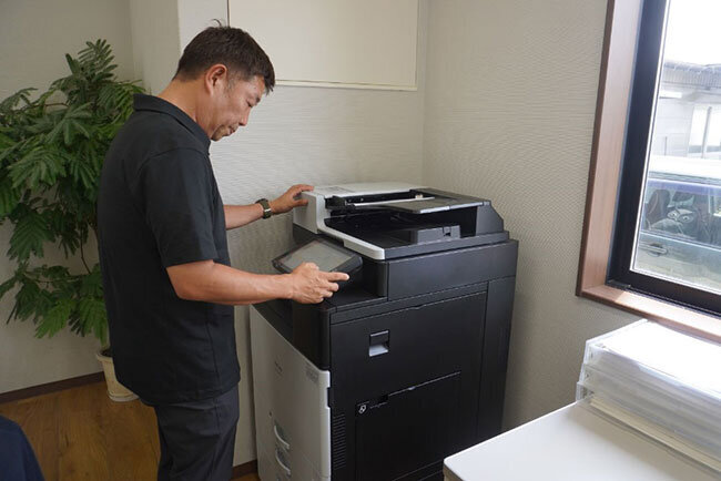 複合機で紙書類をスキャンする様子