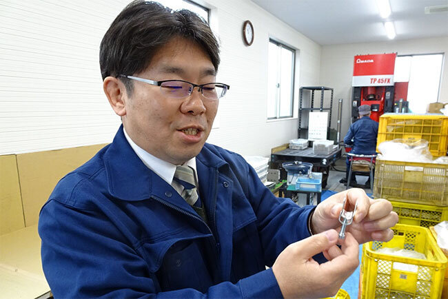 ひんじ検査　電気コードを締め付けるヒンジは「ネジの締め付けと押さえ金具の可動範囲の精緻（せいち）さがカギ」と説明する築比地社長