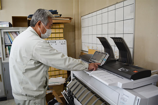 広幅複合機を操作する水田専務。A1サイズの施工図を扱う