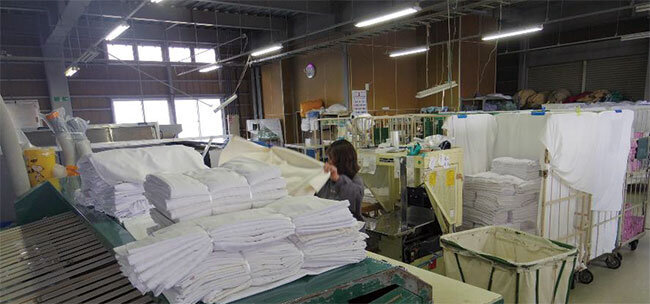 工場で毎日大量のリネン類をクリーニングし宿泊施設に配送する