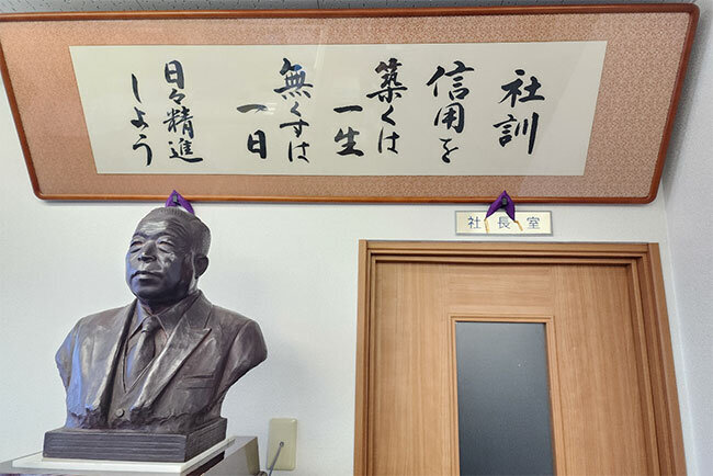 社訓の額縁　　事務所では社訓が額で飾られ、理念の共有に役立っている。銅像は創業者の故・山本了照氏
