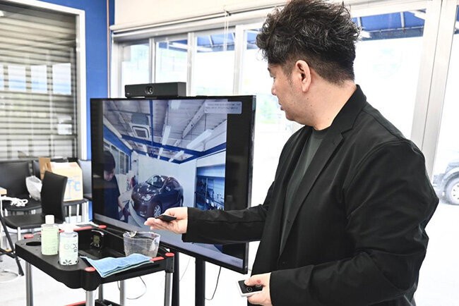 モニター上に設置されたビデオバーを操作する平井社長