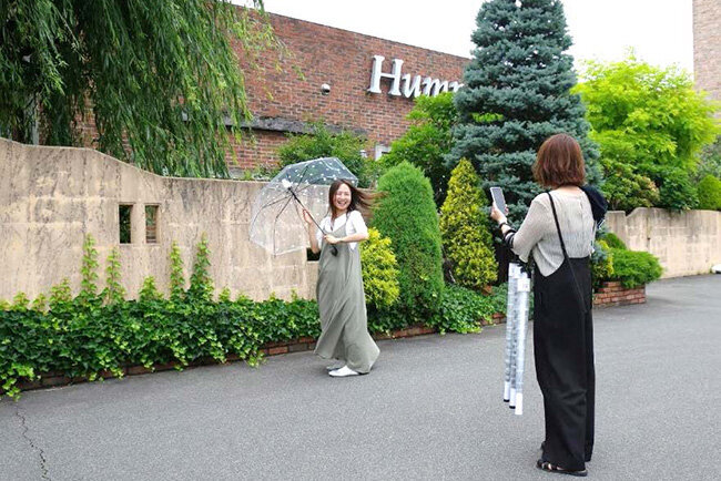 ハンプティーダンプティー本店前でオンラインショッピングサイト用の撮影をする社員