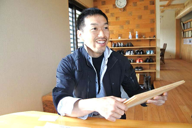 ハウスメーカーの合板の床材を手に話す須永全人代表取締役